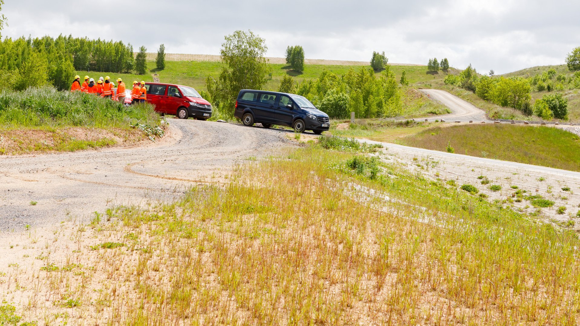 Kleinbusse und Menschengruppe am Rand eines Beckens