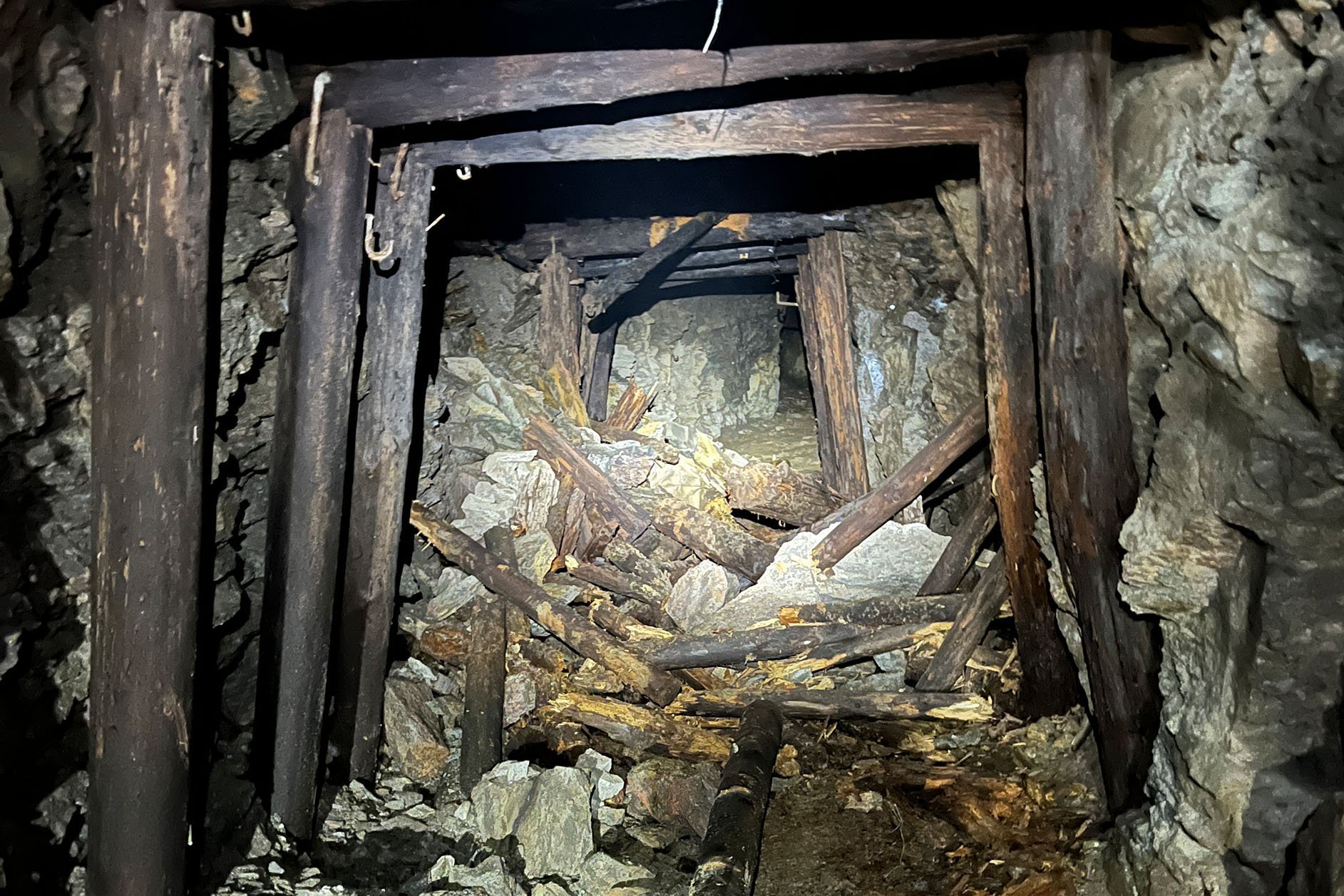 Eine alte Strecke unter Tage mit fauligen Holzstempeln und verbrochenem Profil