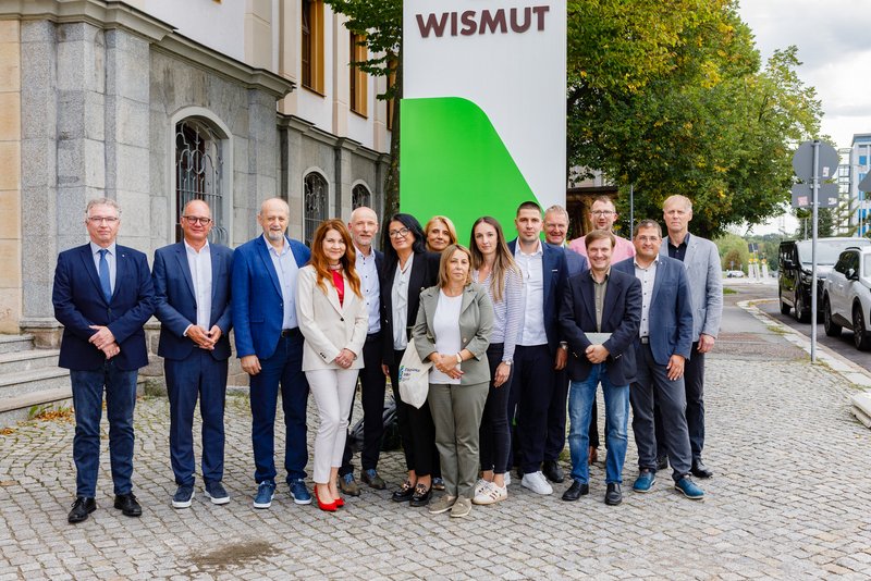 Gruppenbild vor einem Pylon mit Schriftzug Wismut