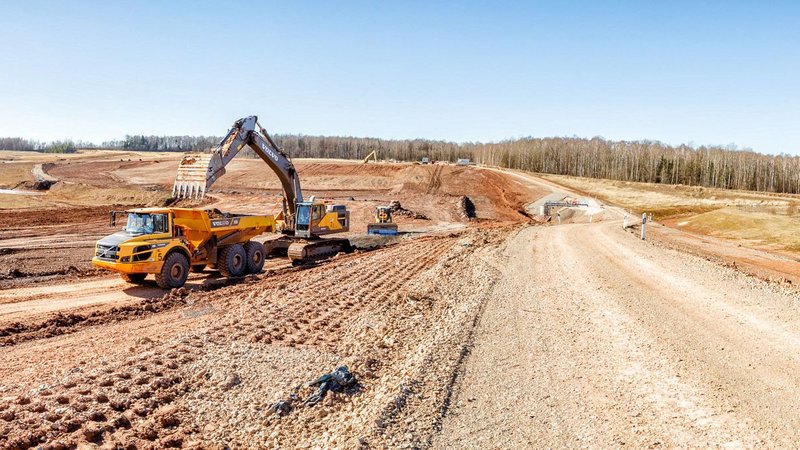 Bagger und Dumper neben einer Fahrtradde, die in den Einschnitt führt