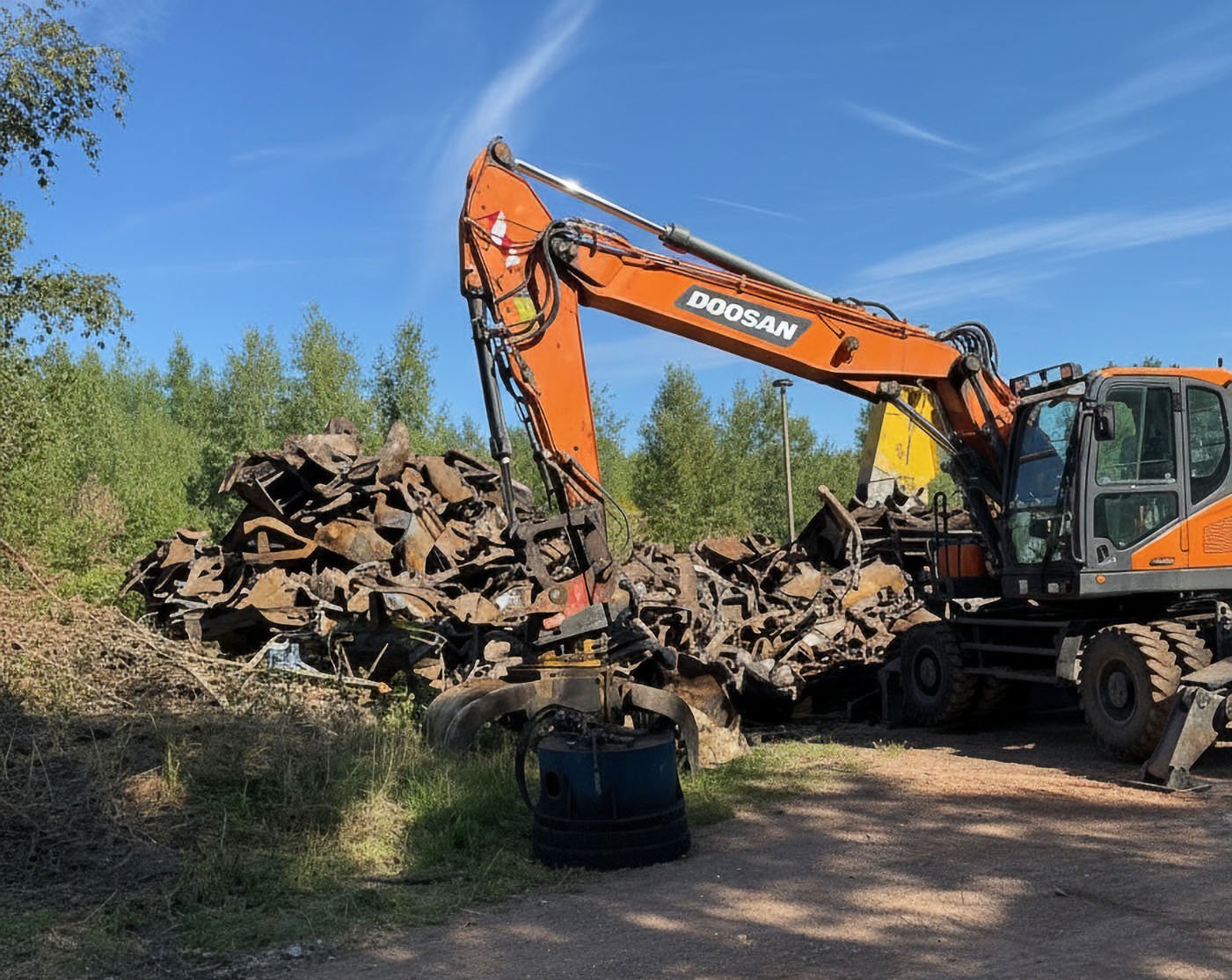 Ein Bagger vor einem Haufen kleiner Schrottteile