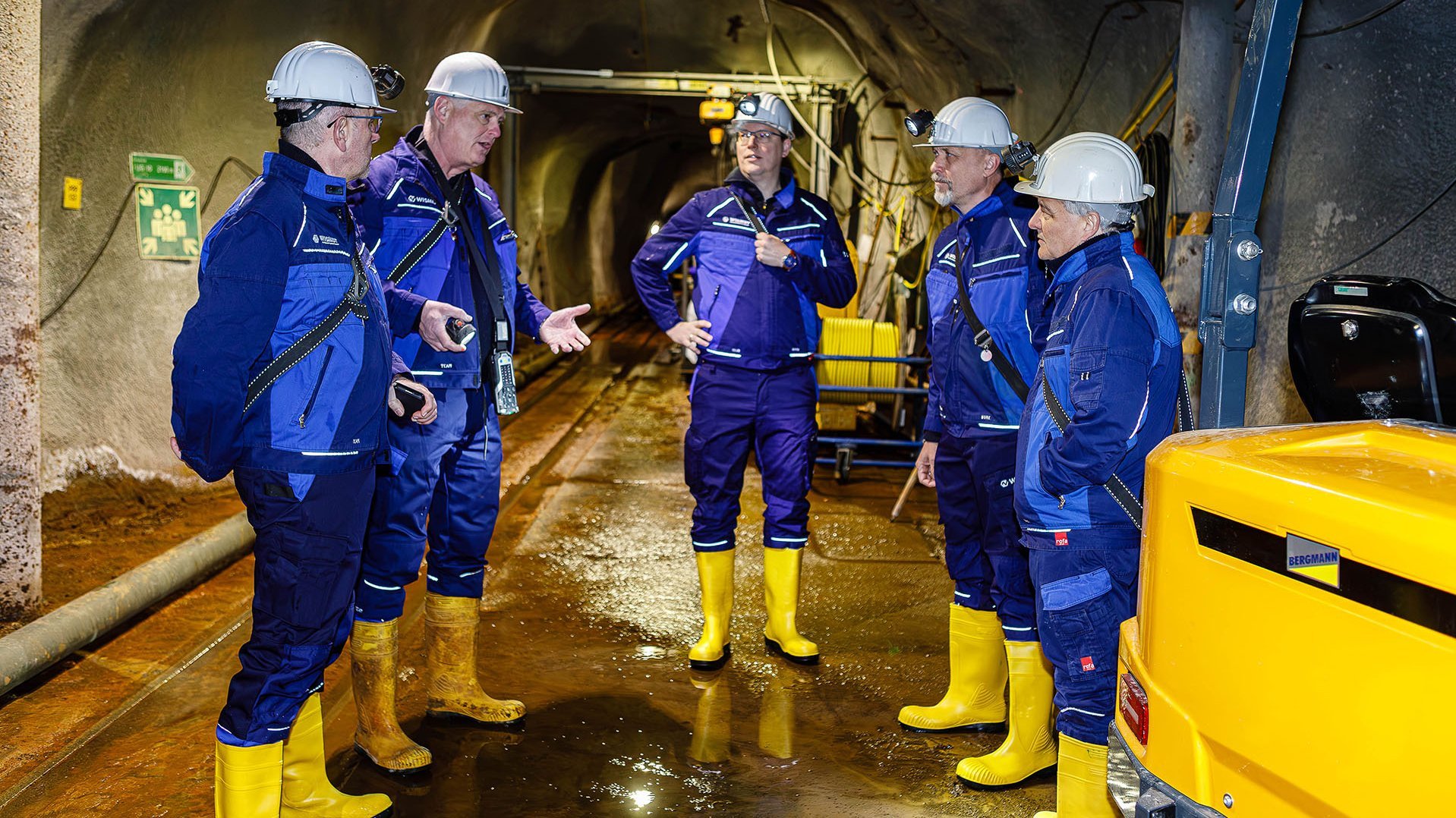 Die Gruppe steht unter Tage zwischen Maschinen