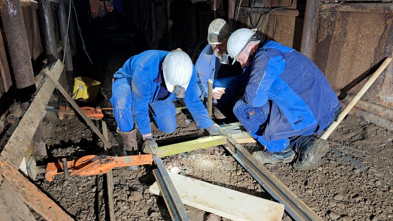 Drei Bergleute richten das neue Gleis aus