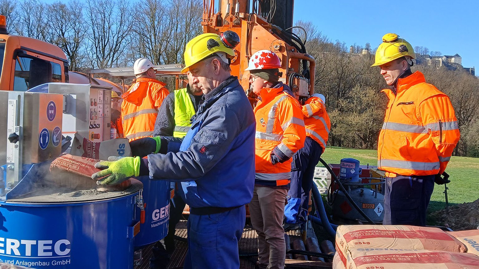 Arbeiter mit Helmen an dem Betonmischer