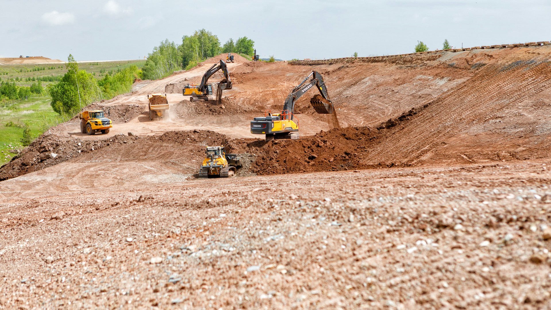 Bagger, Raupen und Dumper tragen einen Damm ab