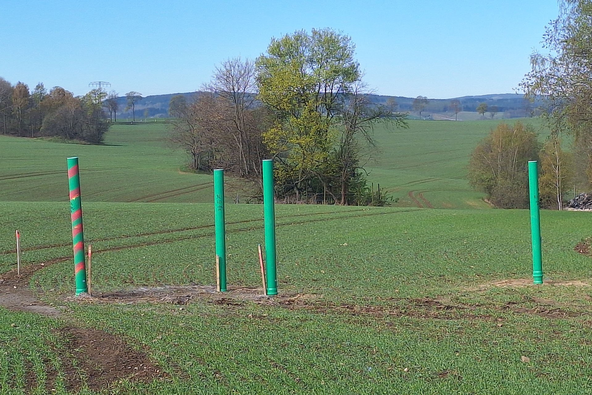 Vier Rohre stehen senkrecht auf einem Feld
