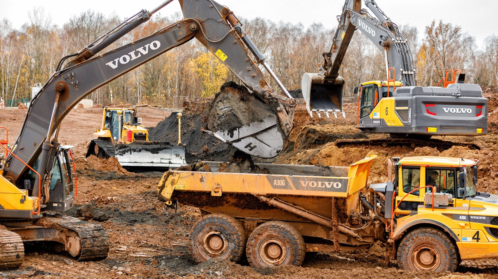 Bagger, Raupen und Dumper tragen schwarzes Tailingsmaterial ab
