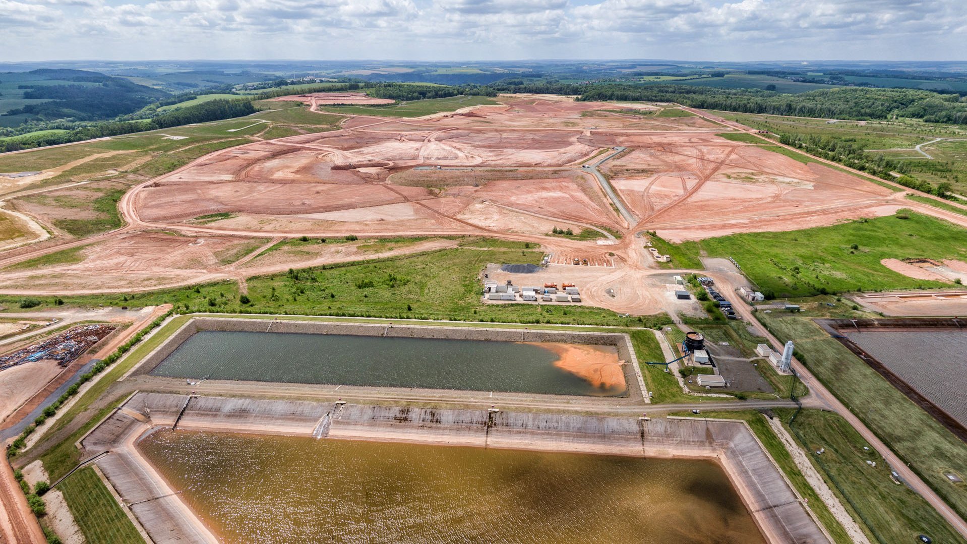 Luftbild mit Wasserbecken und Erdarbeiten auf einer großen Ebene