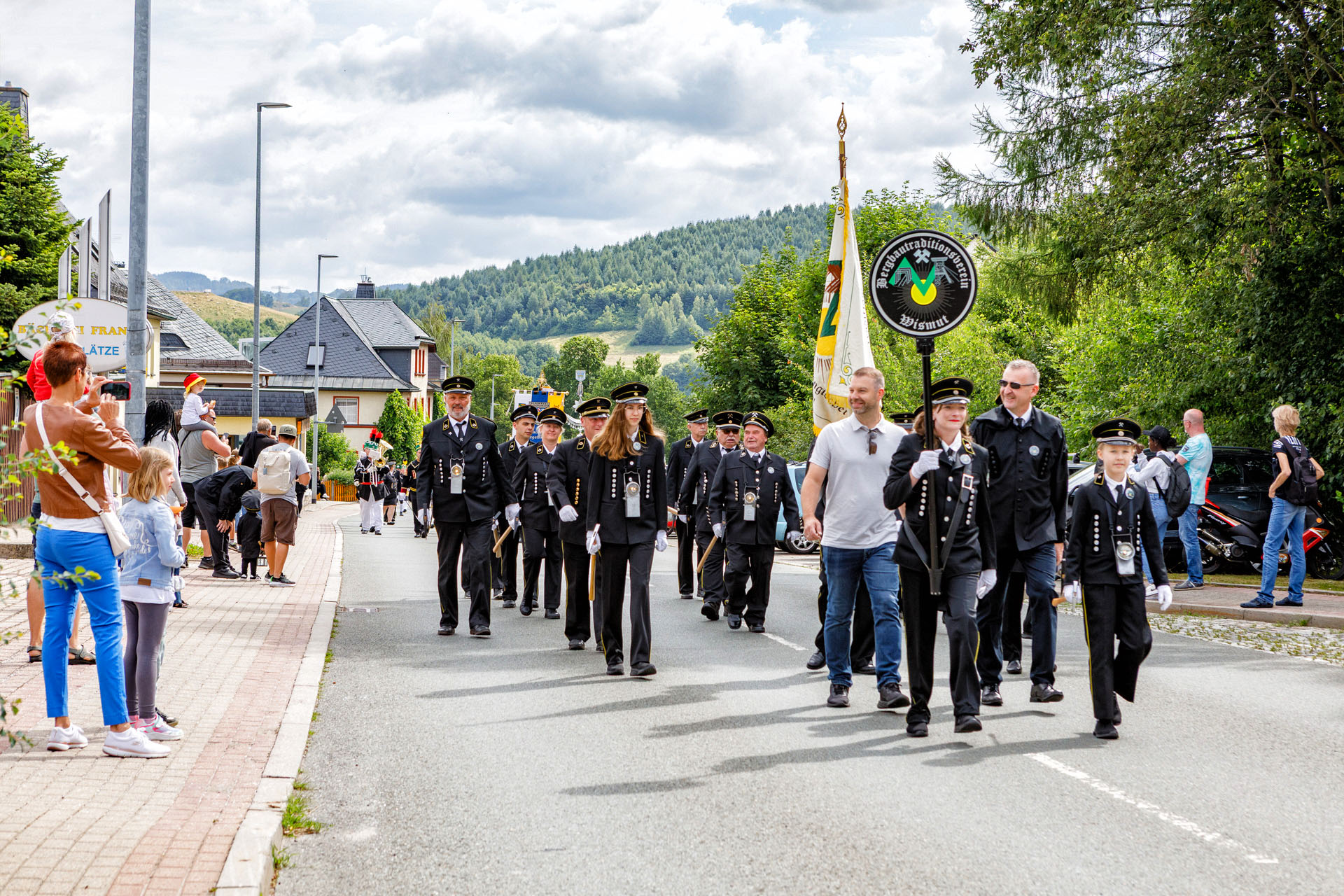 Spitze der Bergparade mit Fahnenträger, Zuschauer an den Straßenrändern