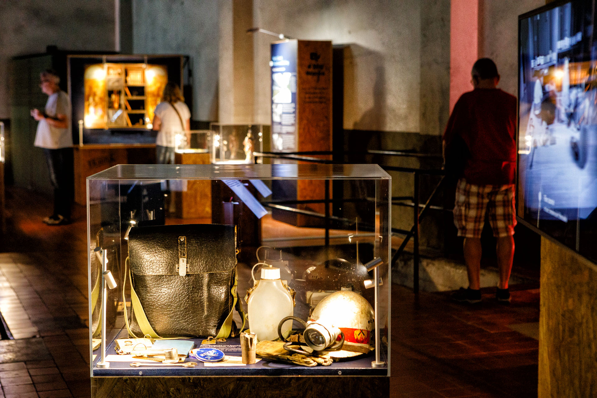 Eine beleuchtete Vitrine mit Habseligkeiten eines Bergmanns (Helm, Tasche, Trinkflasche usw.) in einem dunklen Raum